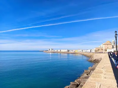 a group of people standing on a wall near the water at El vigía de cadiz in Cádiz