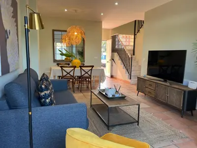 a living room with a blue couch and a tv at Casa piscina playa Barrosa Delfin 7 in Chiclana de la Frontera
