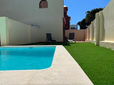 a backyard with a swimming pool and green grass at Casa piscina playa Barrosa Delfin 7 in Chiclana de la Frontera