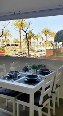 a table with plates and glasses on it with palm trees at Playa Doñana 1 in Sanlúcar de Barrameda