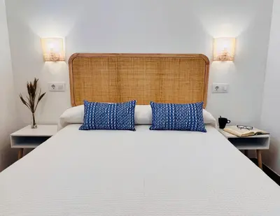 a bedroom with a large white bed with blue pillows at Villa Horacia - Playa de la Jara con Piscina in Sanlúcar de Barrameda