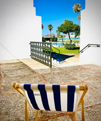 a yellow and blue chair sitting in front of a pool at Villa Horacia - Playa de la Jara con Piscina in Sanlúcar de Barrameda