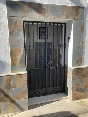a gate on the side of a stone building at La Casa de la Fuente in Sanlúcar de Barrameda