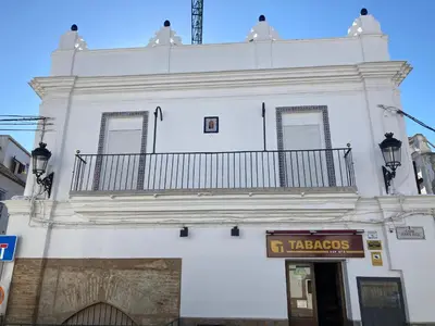 a white building with a balcony on top of it at La Casa de la Fuente in Sanlúcar de Barrameda