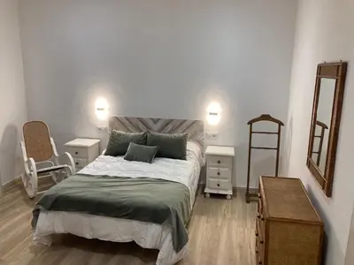 a bedroom with a large bed and a mirror at La Casa de la Fuente in Sanlúcar de Barrameda
