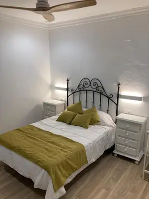 a bedroom with a bed with two night stands and two tables at La Casa de la Fuente in Sanlúcar de Barrameda
