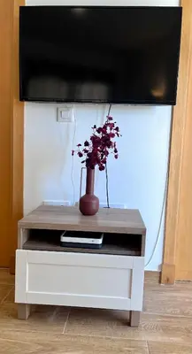a vase with flowers sitting on a tv stand at GATU Villa Atardecer en la playa de las Redes 