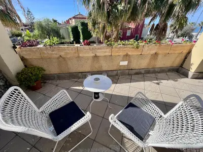 two wicker chairs and a table with a pillow on a patio at GATU Villa Atardecer en la playa de las Redes 