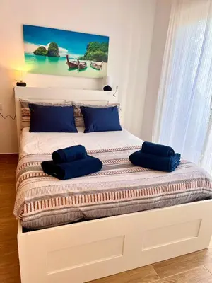 a bed with two blue pillows on top of it at GATU Villa Atardecer en la playa de las Redes 