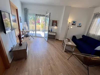 a living room with a blue couch and a wooden floor at GATU Villa Atardecer en la playa de las Redes 