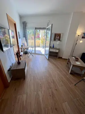 a living room with a wooden floor and a sliding glass door at GATU Villa Atardecer en la playa de las Redes 