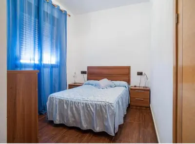 a bedroom with a bed with blue curtains and a wooden floor at CASA VARAVILLA in Conil de la Frontera