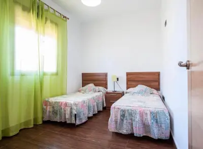 two beds in a room with green curtains at CASA VARAVILLA in Conil de la Frontera