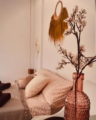 a vase with flowers on a table next to a bed at Loft céntrico con gran terraza in El Puerto de Santa María