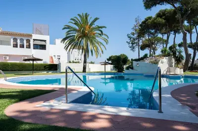 a swimming pool with palm trees and a building at Apartoyou - Vistahermosa in El Puerto de Santa María