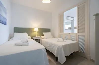 two beds in a room with a window at Apartoyou - Vistahermosa in El Puerto de Santa María