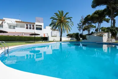 a large blue swimming pool in front of a house at Apartoyou - Vistahermosa in El Puerto de Santa María