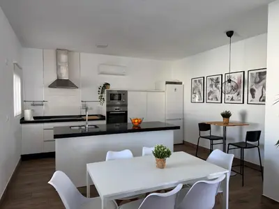 a white kitchen with a white table and chairs at Villa Armonía in Arcos de la Frontera
