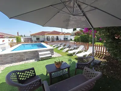 a patio with chairs and an umbrella and a pool at Las Salinas in Chiclana de la Frontera