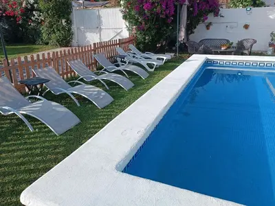 a row of lawn chairs next to a swimming pool at Las Salinas in Chiclana de la Frontera
