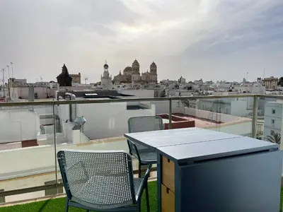 a table and chairs on a balcony with a view of a city at Skyline - Loft with private terrace and breathtaking views! in Cádiz