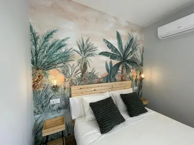 a bedroom with a mural of palm trees on the wall at Skyline - Loft with private terrace and breathtaking views! in Cádiz
