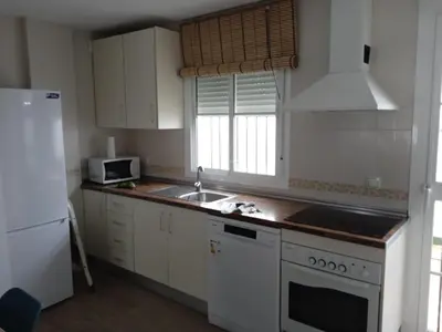 a kitchen with white cabinets and a sink and a refrigerator at Villa Mar in Chiclana de la Frontera