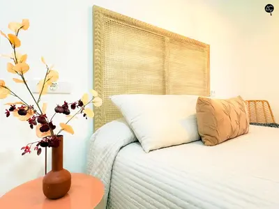 a bedroom with a bed and a vase with flowers on a table at El Encanto de la Playa Santa Mª Grupo AC Gestion in Cádiz