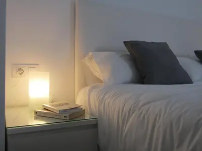 a bed with a side table with a lamp and two books at Apartamentos Santa María 15 in Jerez de la Frontera