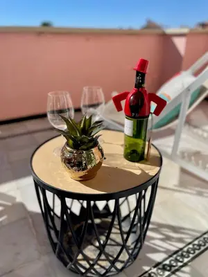 a table with wine glasses and a bottle and a plant at GATU Villa Océano frente al mar en Puerto Sherry 