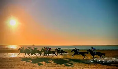 a group of people riding horses on the beach at sunset at Arenas de Sanlúcar II in Sanlúcar de Barrameda