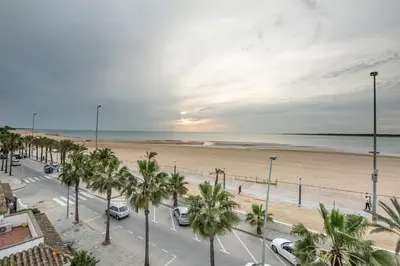 a street with palm trees and a beach at Arenas de Sanlúcar II in Sanlúcar de Barrameda