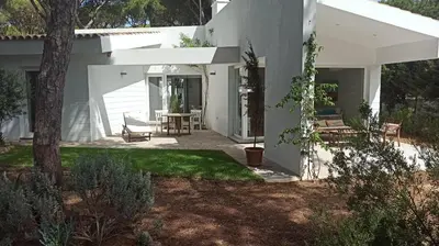 a white house with a patio and a table at Diseño y luz entre los pinos in Chiclana de la Frontera
