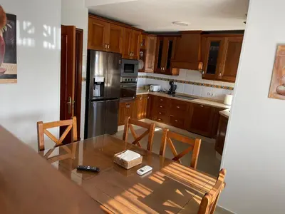 a kitchen with a table and a refrigerator and cabinets at Casa Inés in Sanlúcar de Barrameda