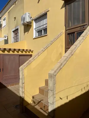 a yellow building with a staircase in front of a house at Casa Inés in Sanlúcar de Barrameda