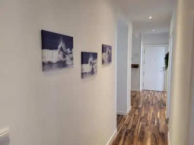 a hallway with three paintings on a wall at La Playita Santa María Beach in Cádiz