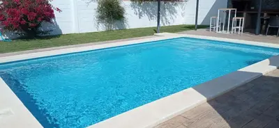 a swimming pool with blue water in a yard at Casa La Cabaña - Solo Familias in Chiclana de la Frontera