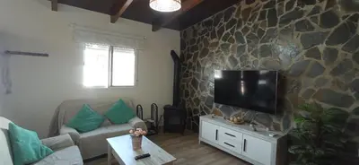 a living room with a tv on a stone wall at Casa La Cabaña - Solo Familias in Chiclana de la Frontera