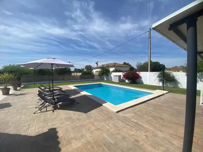 a swimming pool with two chairs and an umbrella at Casa La Cabaña - Solo Familias in Chiclana de la Frontera