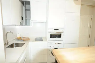 a white kitchen with a sink and a dishwasher at Apartamento reformado con vistas al mar in Cádiz