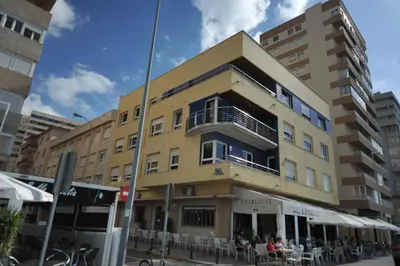 a yellow building with people sitting outside of it at Apartamento reformado con vistas al mar in Cádiz