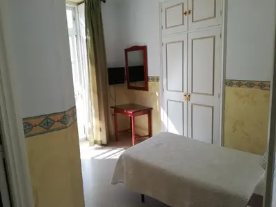 a room with a bed and a table and a mirror at Nuevo Hotel in Jerez de la Frontera