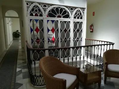 a hallway with chairs and a table and stained glass window at Nuevo Hotel in Jerez de la Frontera