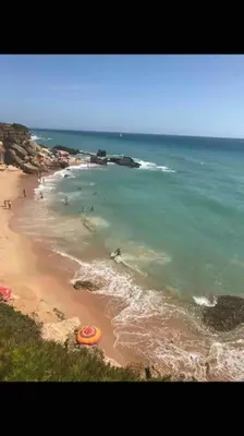 a beach with a group of people in the water at VILLA ANDEMAR in Chiclana de la Frontera