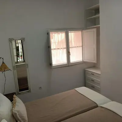 a bedroom with a bed and a dresser and two windows at Jerez Palace House in Jerez de la Frontera