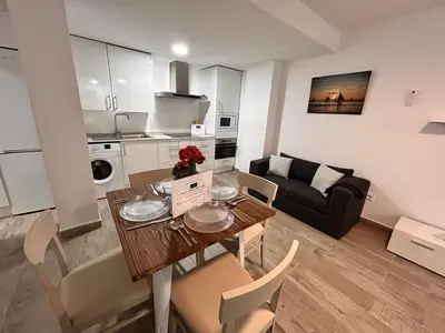 a kitchen and living room with a table and a couch at Apartamento Empul La Barrosa in Chiclana de la Frontera