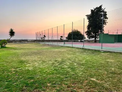 a tennis court with a fence in a field at Apartamento Empul La Barrosa in Chiclana de la Frontera