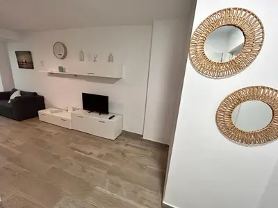 a white living room with a mirror and a tv at Apartamento Empul La Barrosa in Chiclana de la Frontera