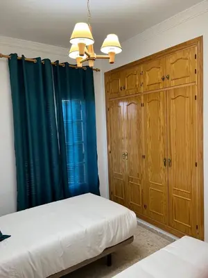 a bedroom with two beds and wooden cabinets at VILLA LA MOMITA in Chiclana de la Frontera