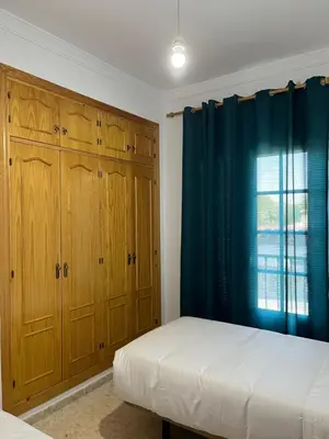 a bedroom with wooden cabinets and a bed and a window at VILLA LA MOMITA in Chiclana de la Frontera